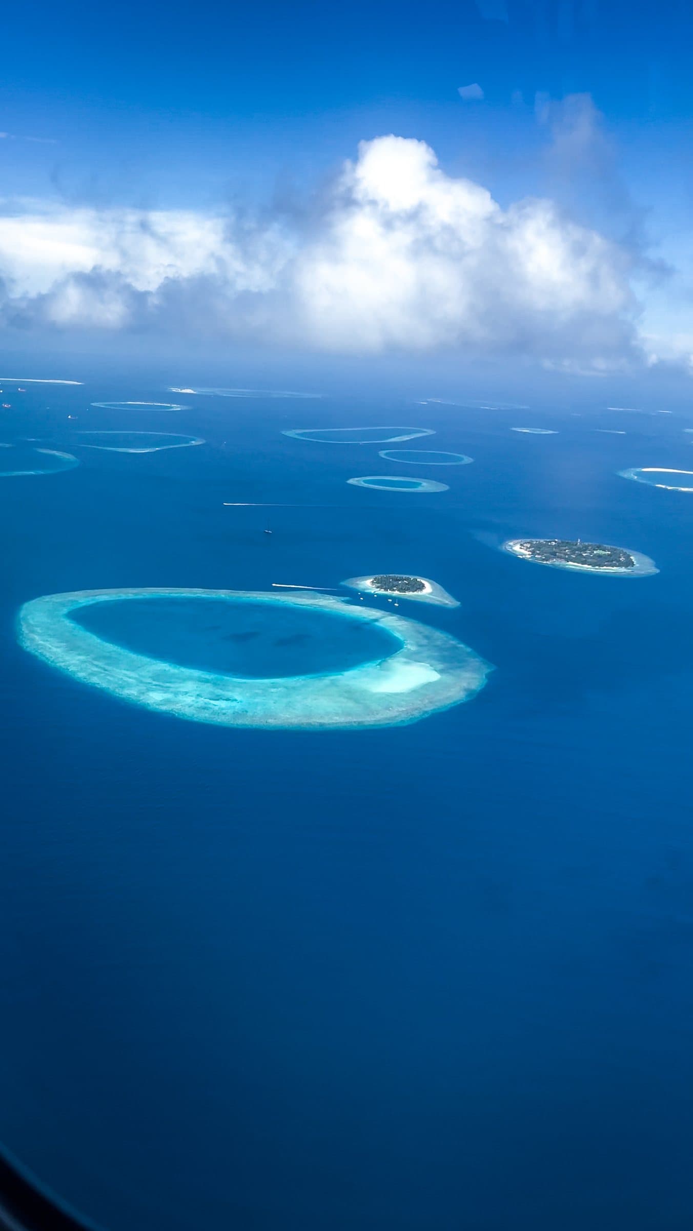Ring-shaped atolls in deep blue ocean seen from a plane window