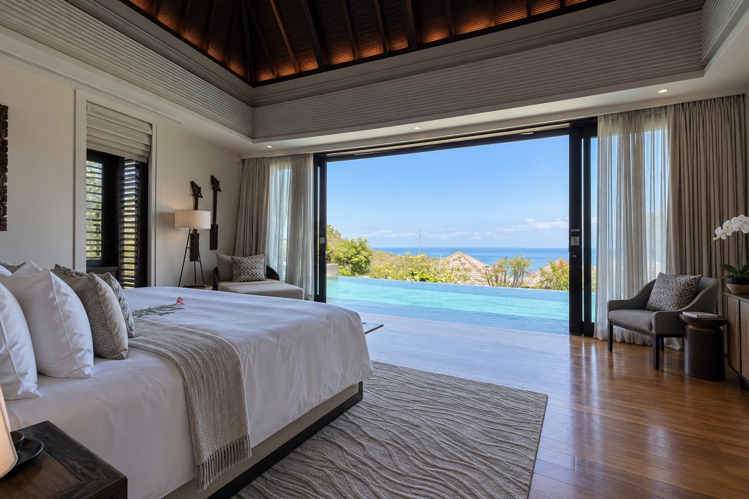 Villa bedroom with the doors open to an infinity pool and the sea