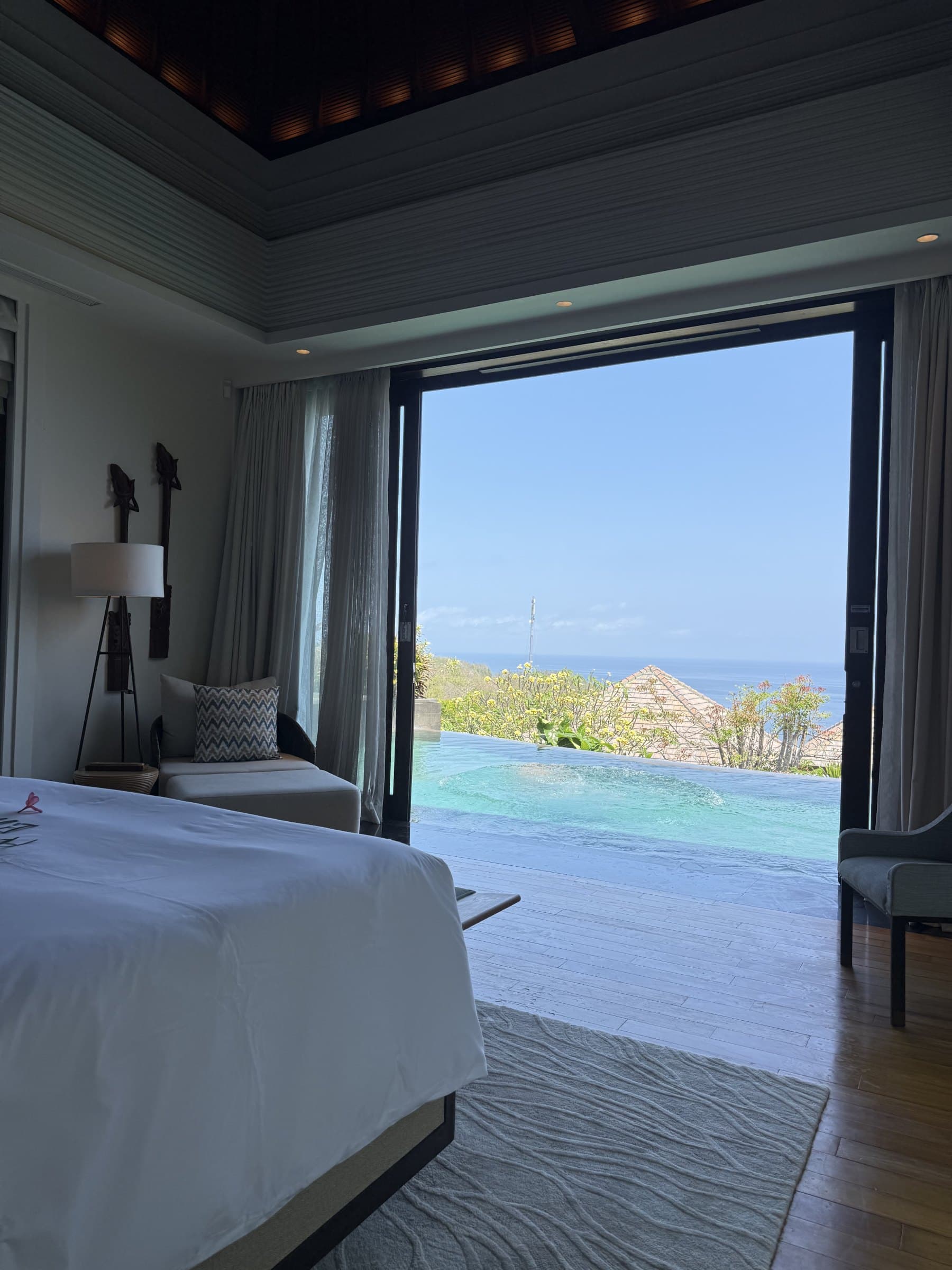 Villa bedroom with the doors open to an infinity pool and the sea