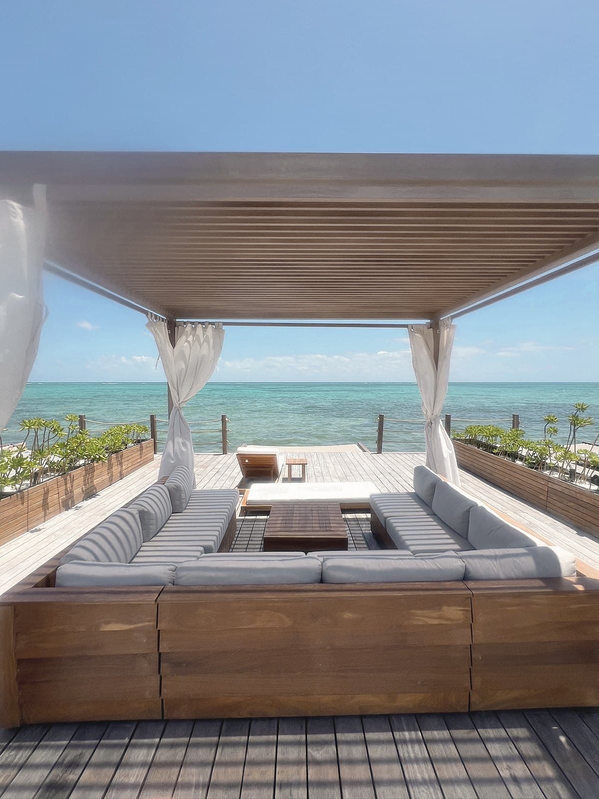 Cabana daybed with white curtains framing the sea