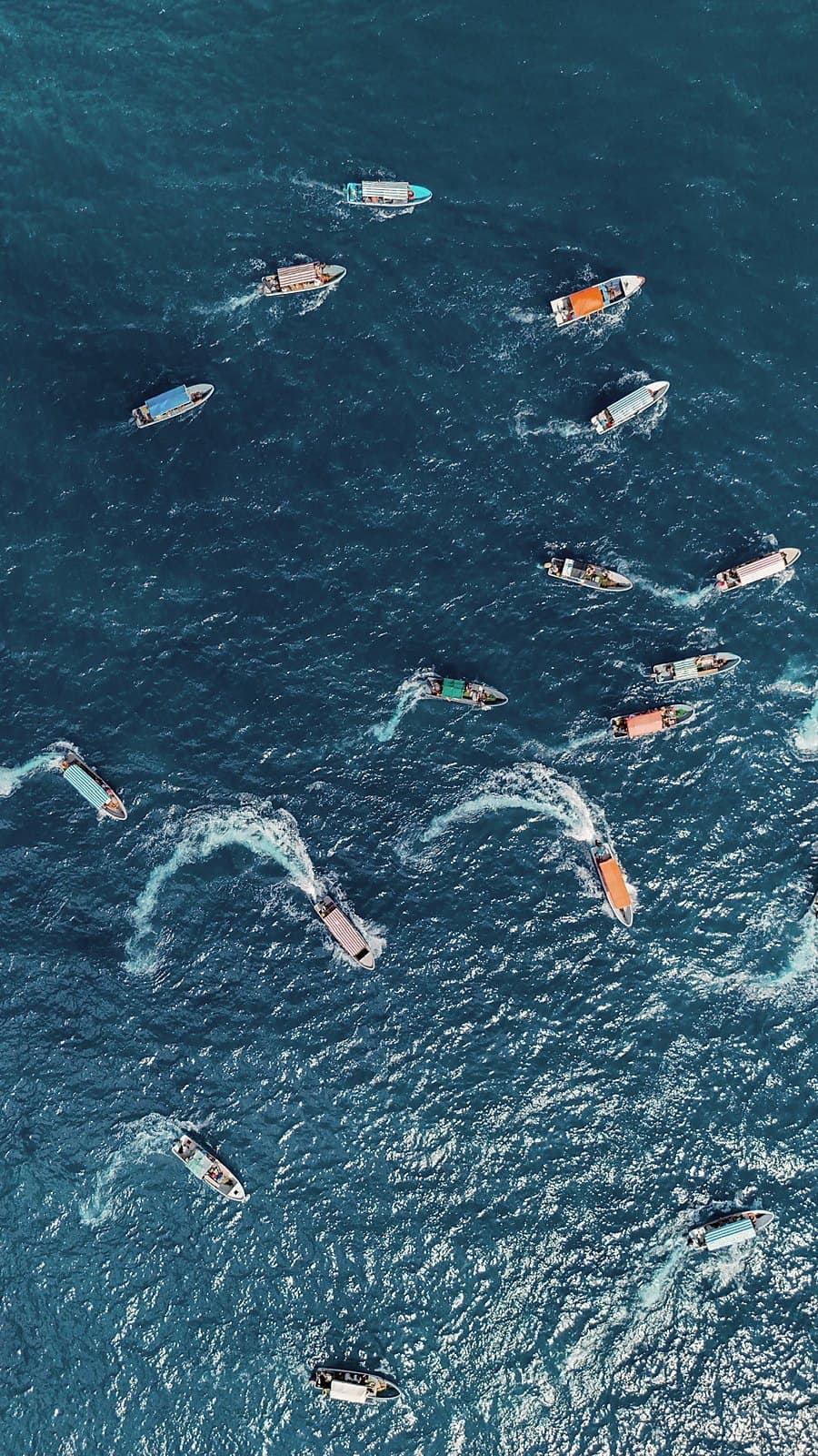 Boats carving white wakes across deep blue water, seen from above