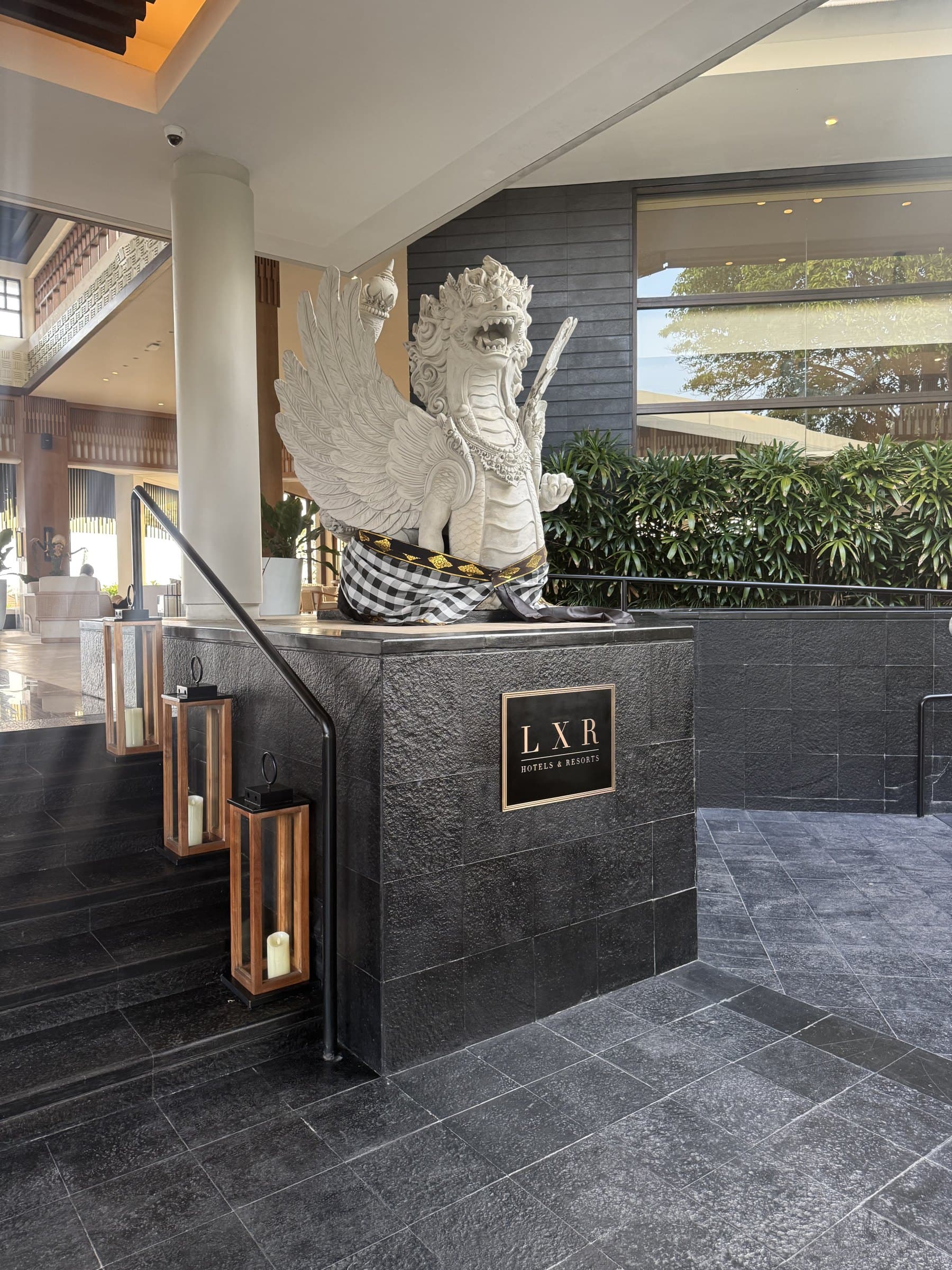 Hotel arrival hall with a carved stone guardian and dark stone floors