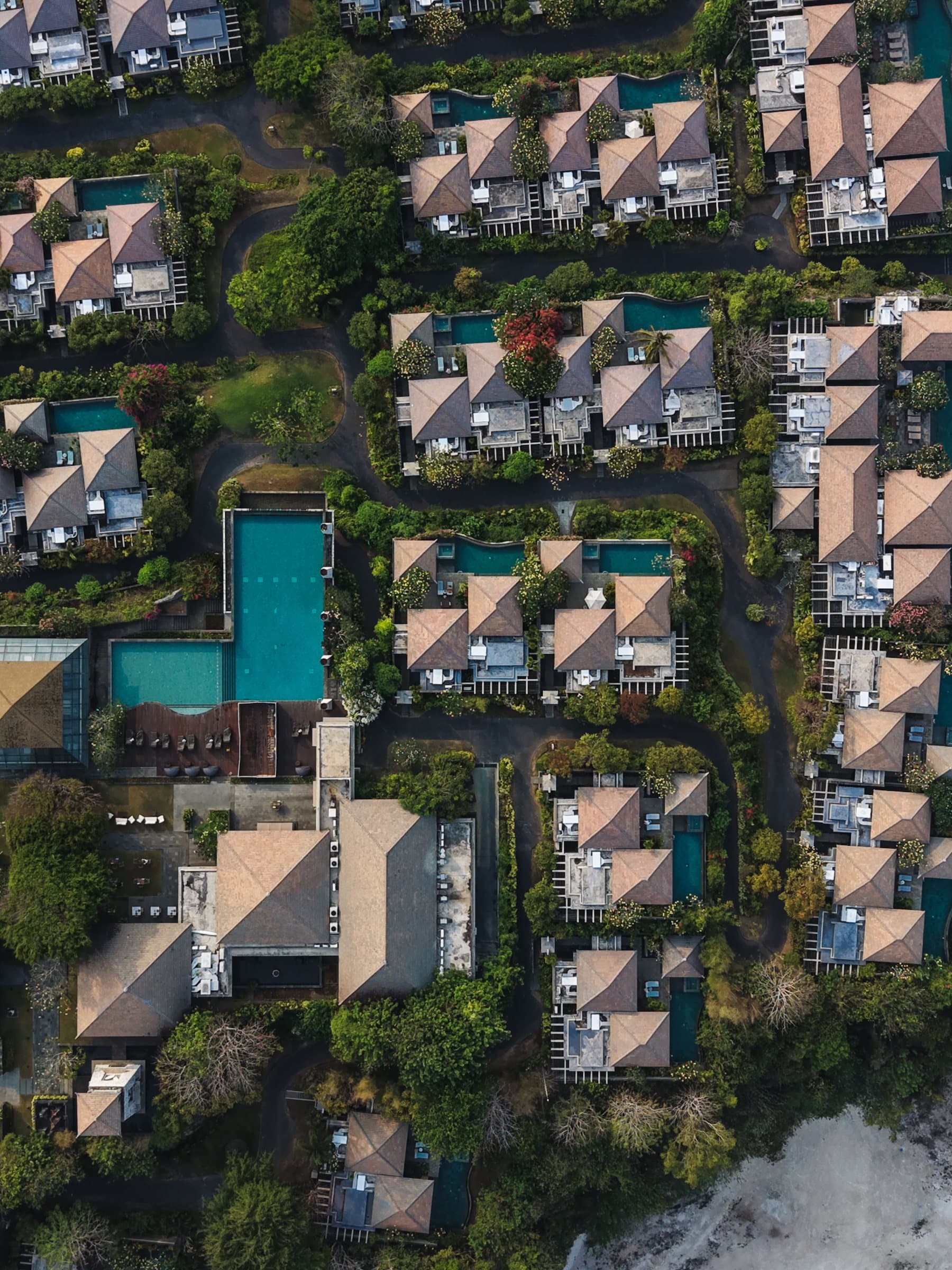 Aerial of villa rooftops and private pools among palms